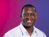 Photo of Emile Heskey in front of a pink and purple gradient background